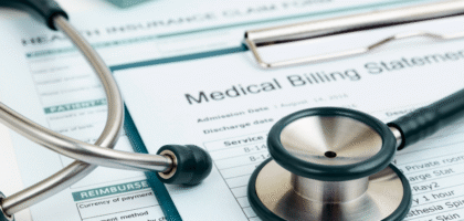 Close-up of a stethoscope, calculator, and health insurance claim form placed on top of a medical billing statement.
