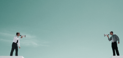 Two people standing on separate platforms using megaphones to talk to each other.