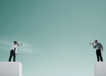 Two people standing on separate platforms using megaphones to talk to each other.